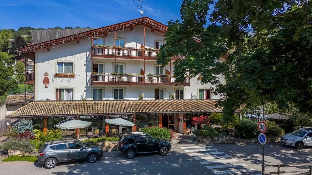 Budynek hotelu Los Andes z drewnianymi balkonami i tarasem od frontu, w otoczeniu zieleni