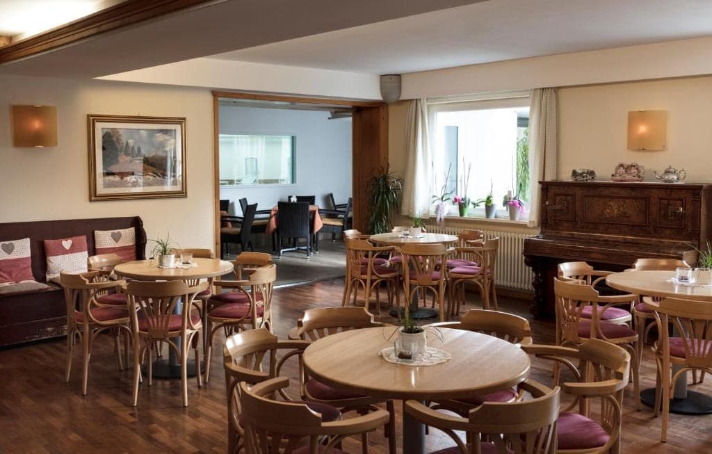 Sala kawiarniana hotelu Los Andes z okrągłymi stołami, wiklinowymi krzesłami i oknami na dolinę