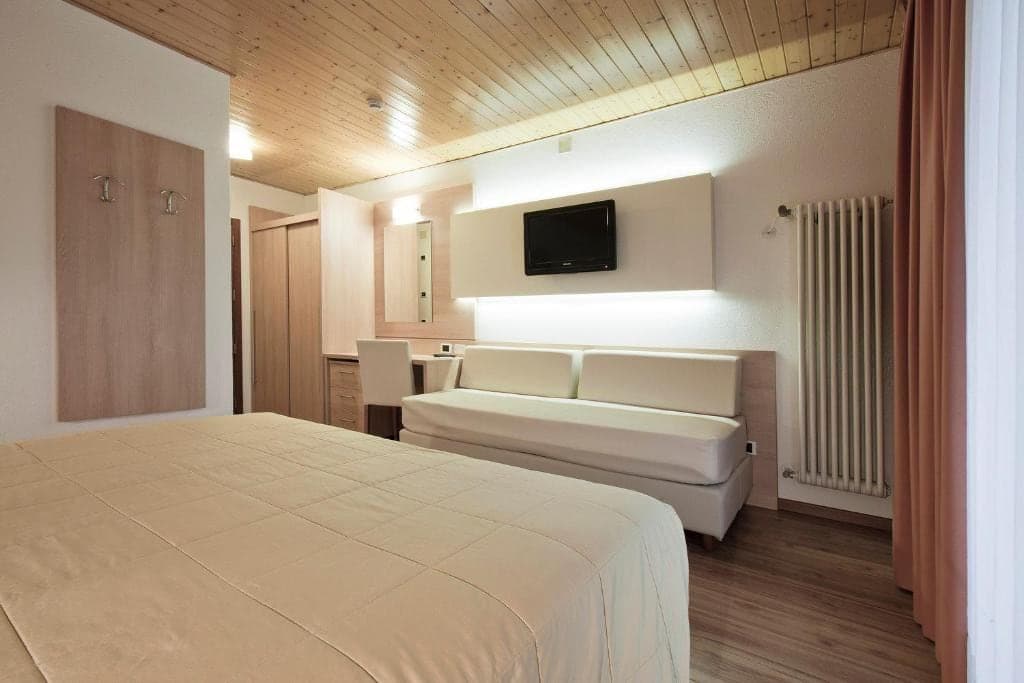 Odnowiony pokój Plus w hotelu Los Andes z jasną sofą, telewizorem i drewnianym sufitem