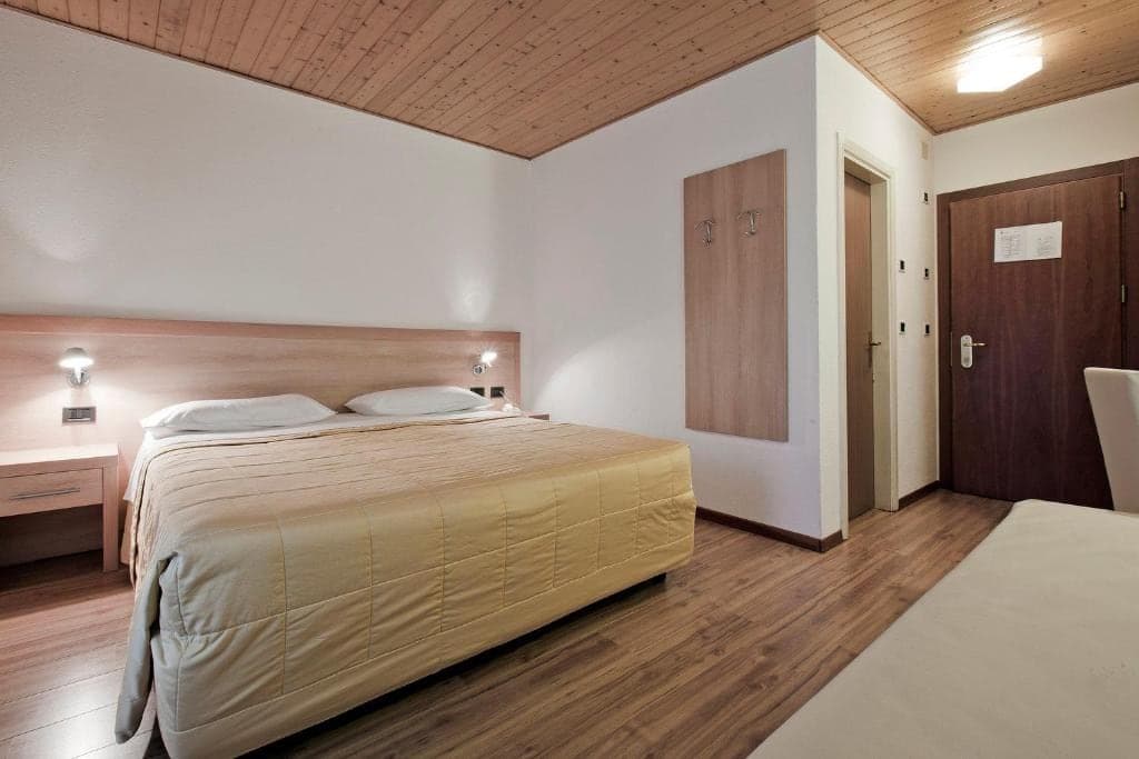 Pokój w hotelu Los Andes z beżową narzutą, przedpokojem i drewnianą podłogą