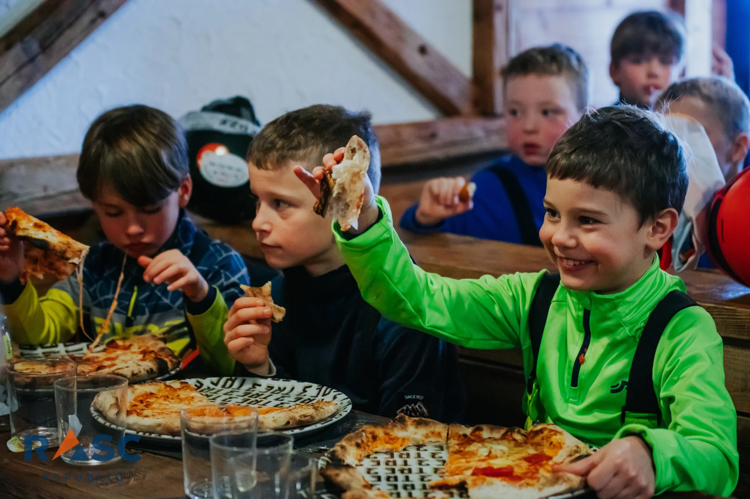 Dzieci przy stole w schronisku, jedzą pizzę po zjeździe
