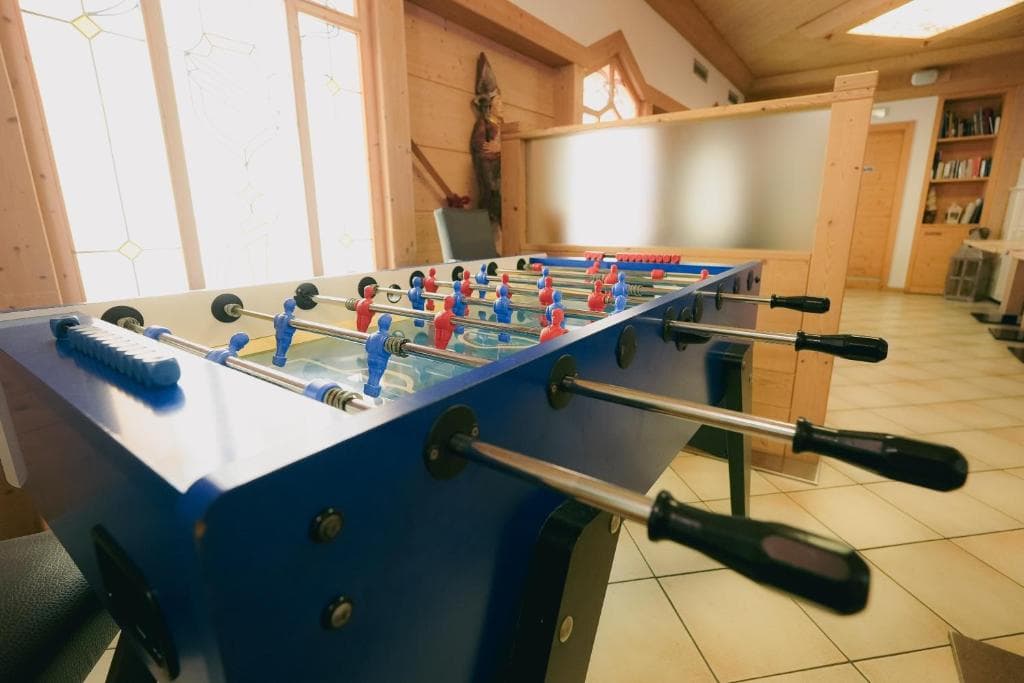 Sala zabaw w hotelu Olimpionico ze stołem do piłkarzyków i drewnianą boazerią