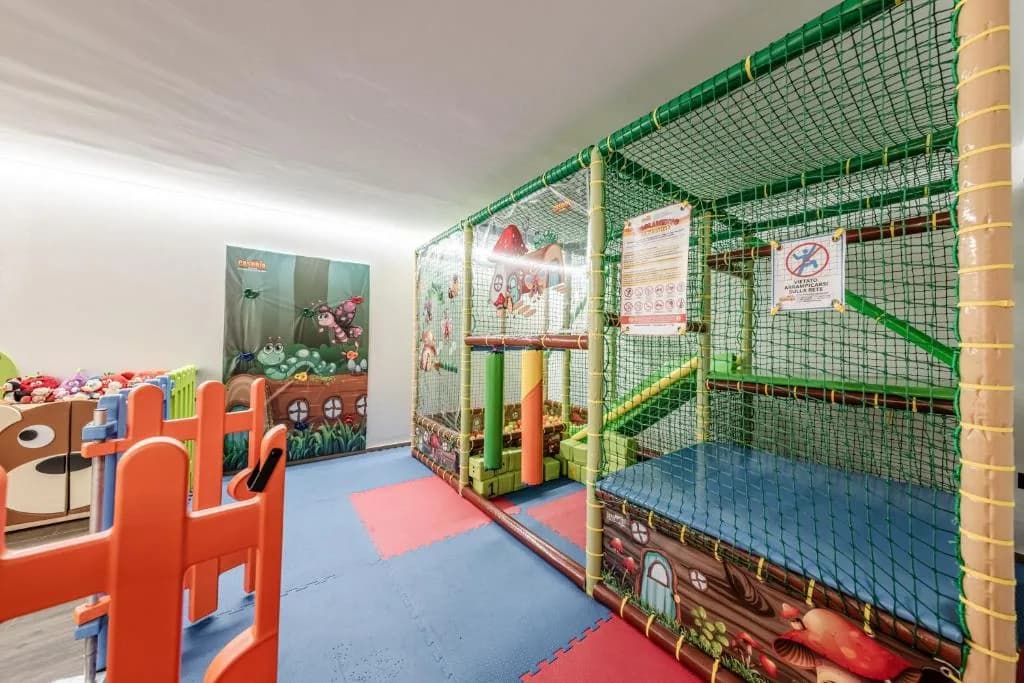 Sala zabaw dla dzieci w rezydencji Gaia z kolorową konstrukcją wspinaczkową i siatkami