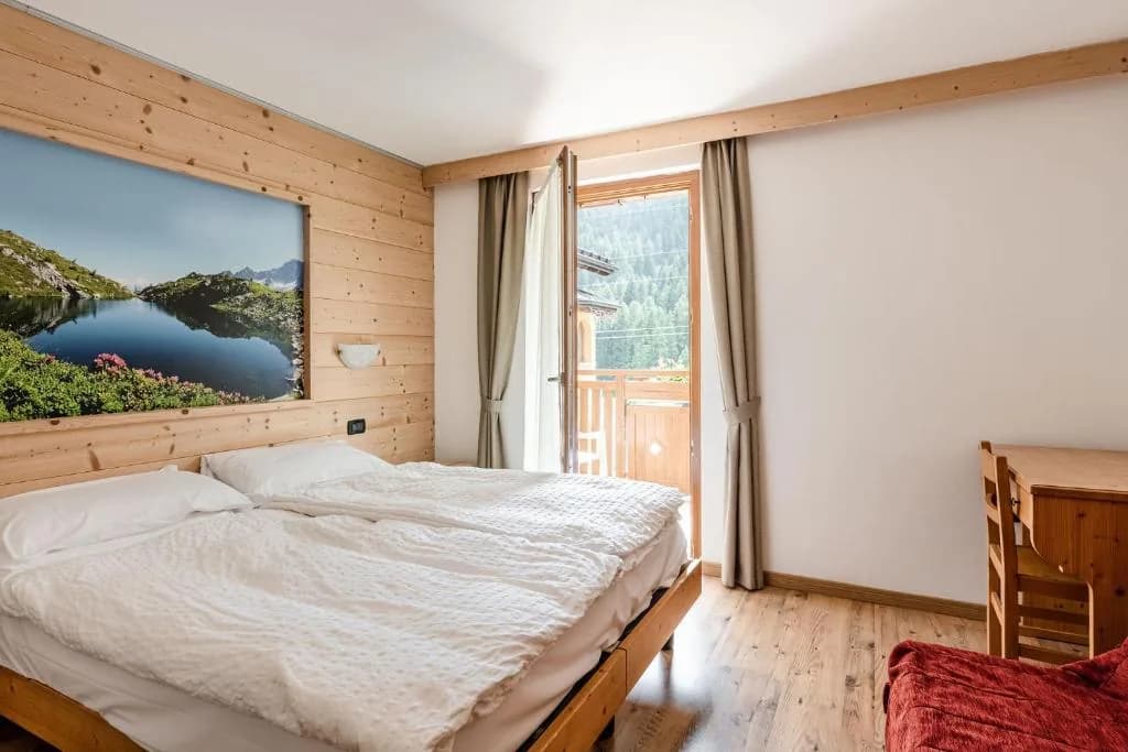 Sypialnia apartamentu z podwójnym łóżkiem i wyjściem na balkon