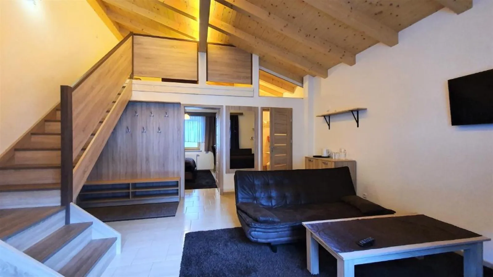 Apartament LUX z antresolą, drewnianymi schodami i sofą w pokoju dziennym