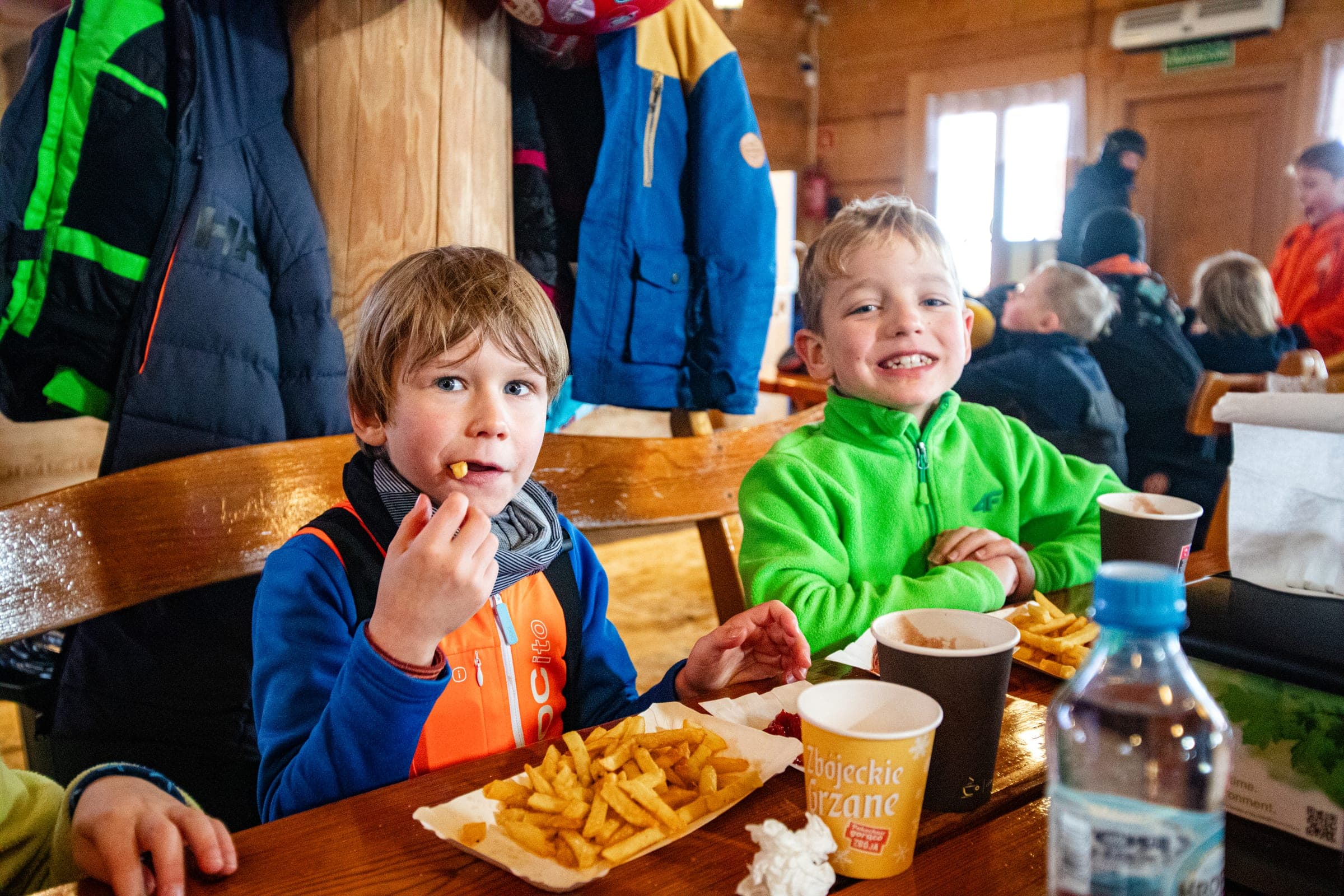 Dwóch chłopców je lunch przy stole w barze na stoku